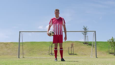 jugador de fútbol de pie con la pelota en el campo