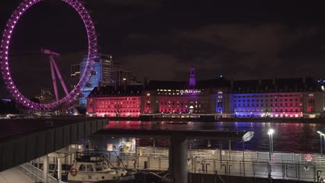 view of london thames river with london eye wheel in the background. beautiful night lights. england capital uk