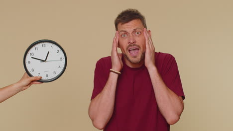 man with anxiety checking time on clock, running late to work, being in delay, deadline