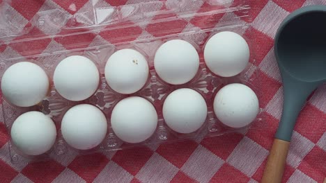 eggs in a carton with utensils on checkered tablecloth