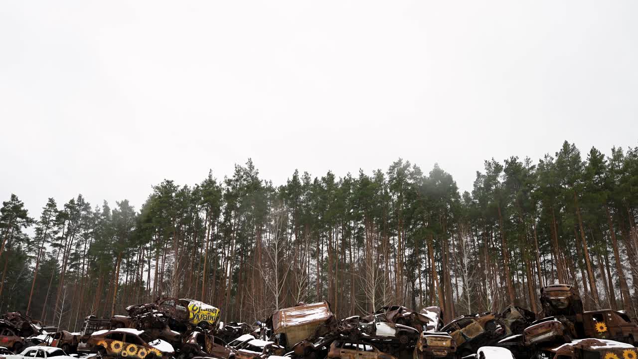 A tilt-down view of a pile of destroyed and burnt cars, stacked on top of each other, is seen in Irpin, Ukraine, during winter, after battles between Ukrainian and Russian forces in the ongoing war.