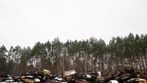a tilt-down view of a pile of destroyed and burnt cars, stacked on top of each other, is seen in irpin, ukraine, during winter, after battles between ukrainian and russian forces in the ongoing war.