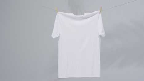 Video-of-white-t-shirt-with-clothes-pegs-and-copy-space-on-grey-background