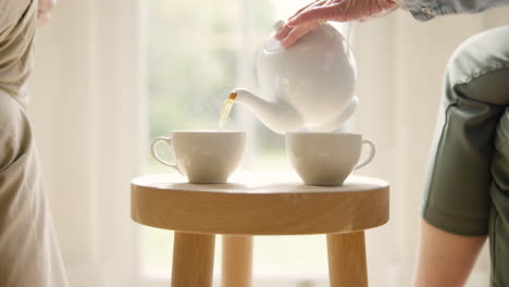 hands, cup and pouring from a teapot closeup