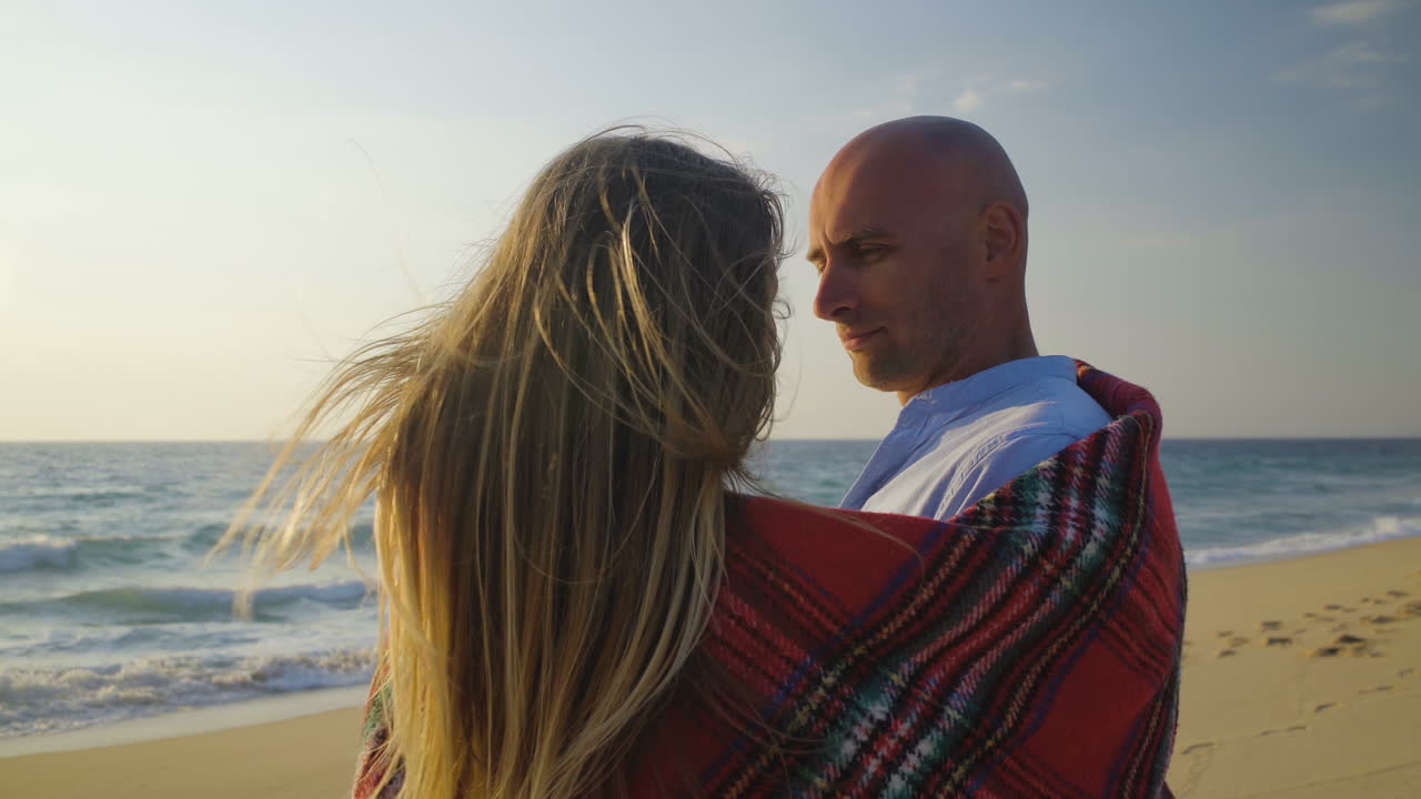 una pareja enamorada besándose en una playa de arena.