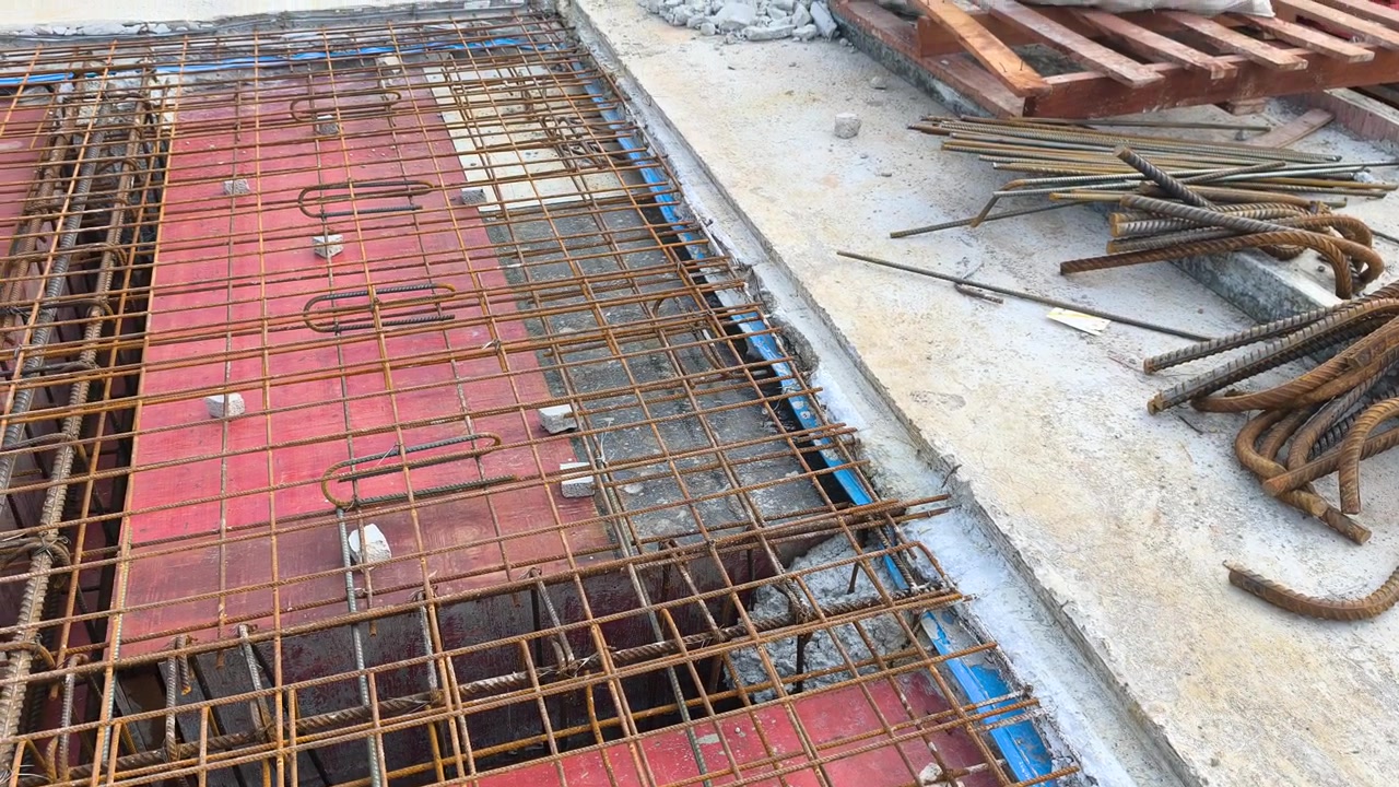 En blå gummivattenspärr är installerad längs en konstruktionsfog i en betongplatta. Den fungerar som en barriär för att förhindra vatteninträngning genom takplattans fogar. Monteringen säkerställer strukturell vattentätning.