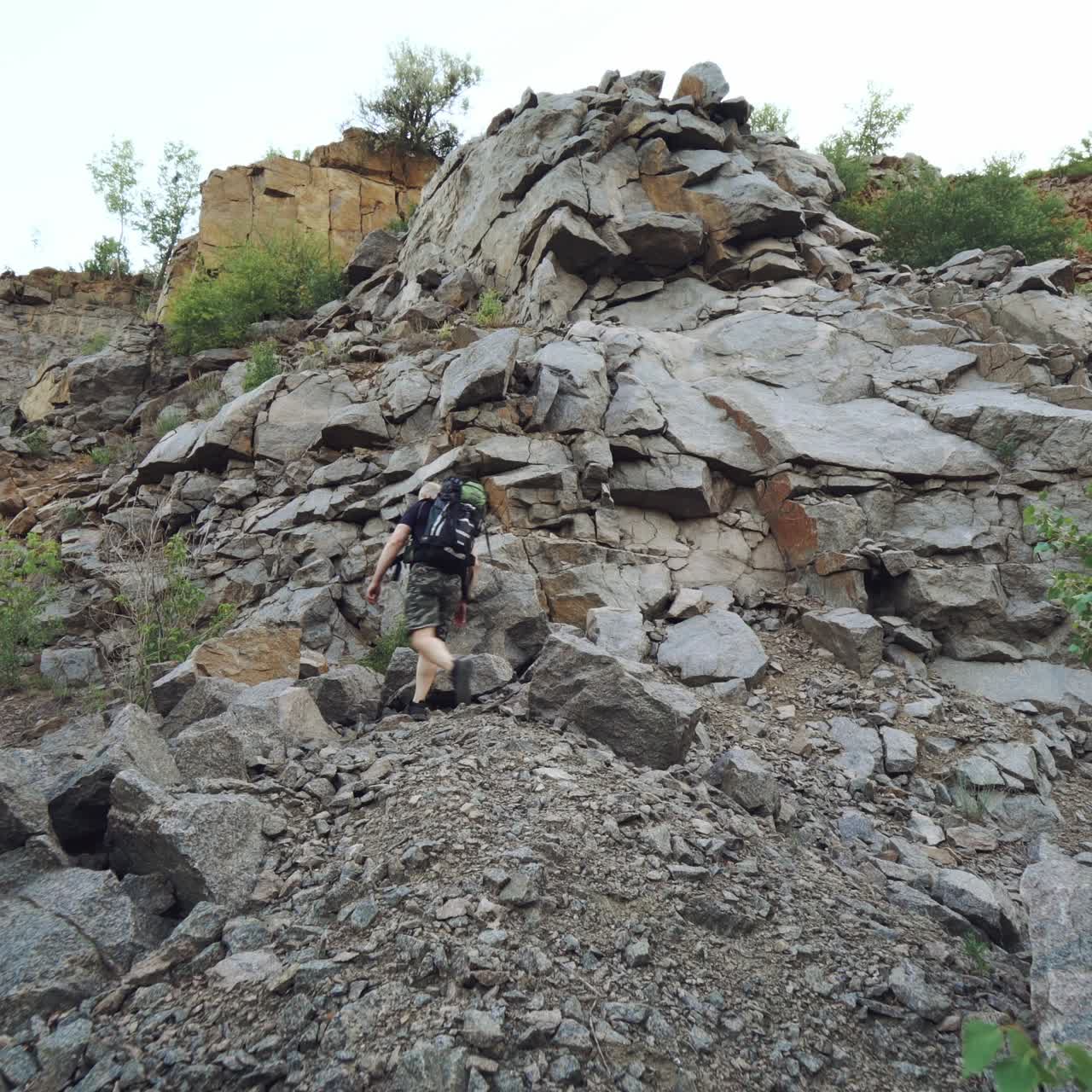 tourist with sports equipment is climbing a rock and viewing a beautiful place from height