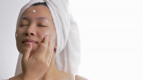 close up of a woman applying a nourishing cream to the face for natural skincare