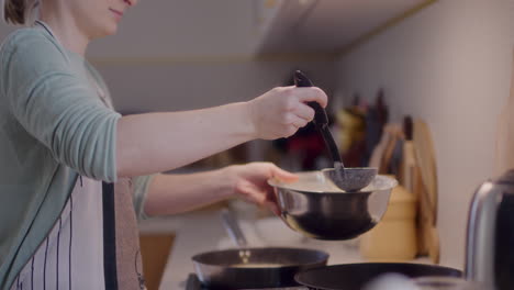 woman scooping pancake batter with ladle in kitchen while cooking