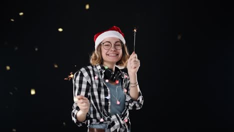 Una-Linda-Mujer-Con-Gorro-De-Papá-Noel-Y-Coloridas-Guirnaldas-Y-Auriculares-En-El-Cuello-Con-Dos-Bengalas-Bailan-En-La-Fiesta-De-La-Noche-De-Navidad-Sobre-Fondo-Negro.-Mujer-Joven-Sonriente-Y-Alegre-Divirtiéndose