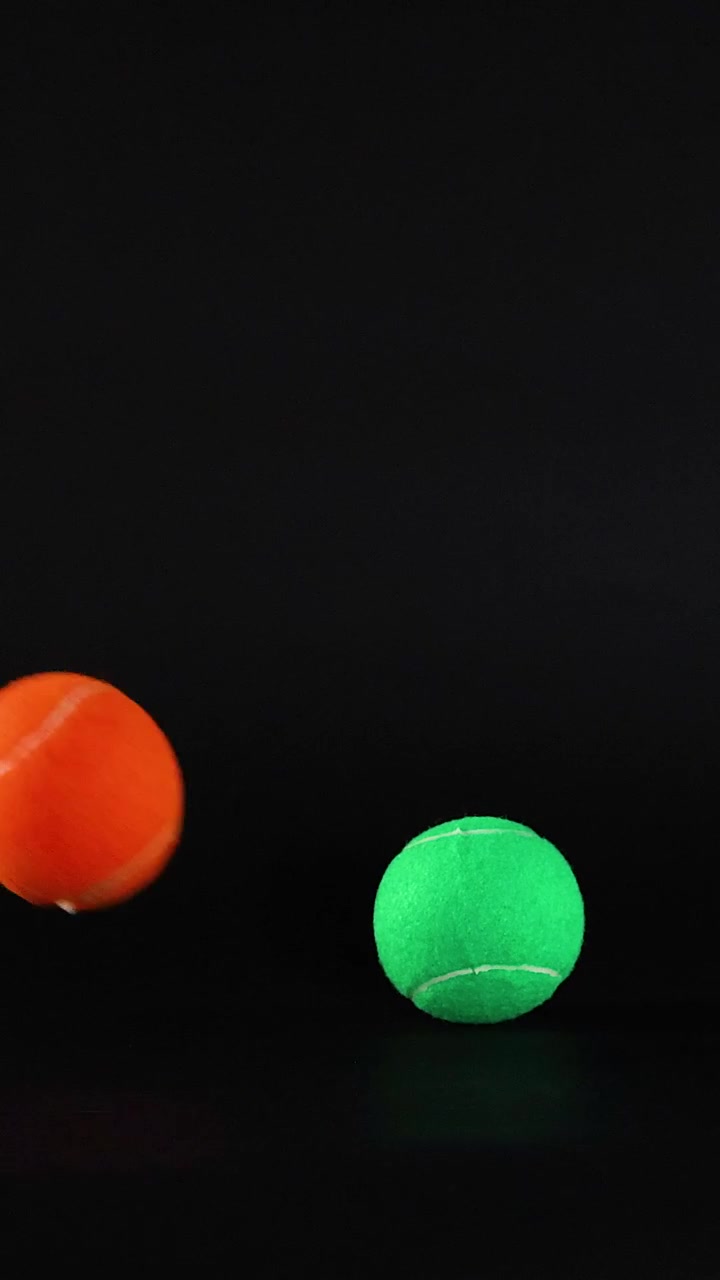 Green and orange balls moving against black background