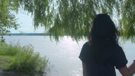 Mujer-Al-Lado-De-Un-árbol-Mirando-Hacia-Un-Vasto-Río