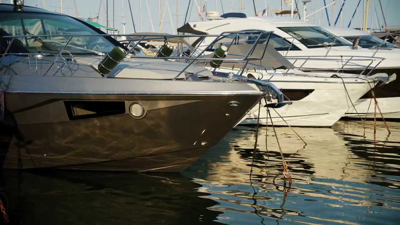 Motoscafi e yacht moderni ormeggiati nel porto turistico di Cannes sotto la calda luce del sole serale.