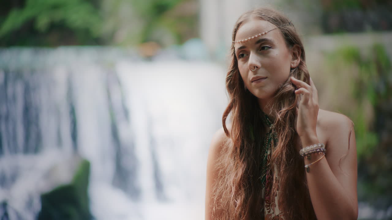 una mujer pensativa frente a una cascada está buscando inspiración y paz