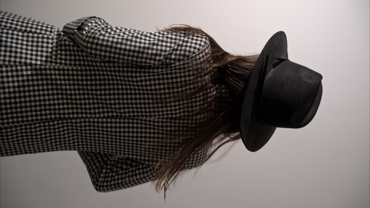 섹시한 라틴 여성 모델의 수직 느린 동작 재과 검은 모자를 입고 미소 짓고 카메라를 위해 돌아갑니다.