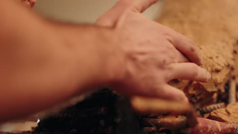 close up of clay being applied to metal base during sculpting process indoors