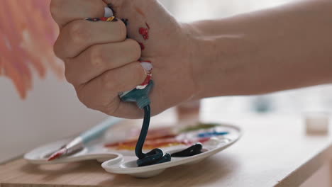Art-student-squeezes-dark-blue-paint-into-cup-on-palette