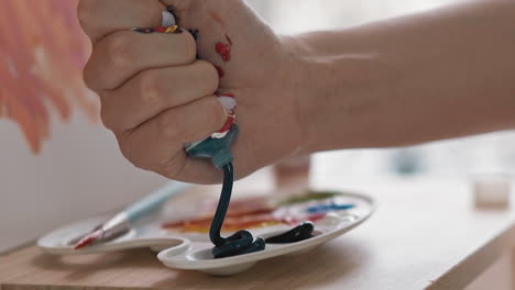 art student squeezes dark blue paint into cup on palette