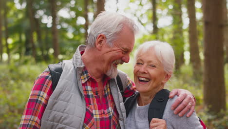 portrait of loving retired senior couple walking in woodland countryside together