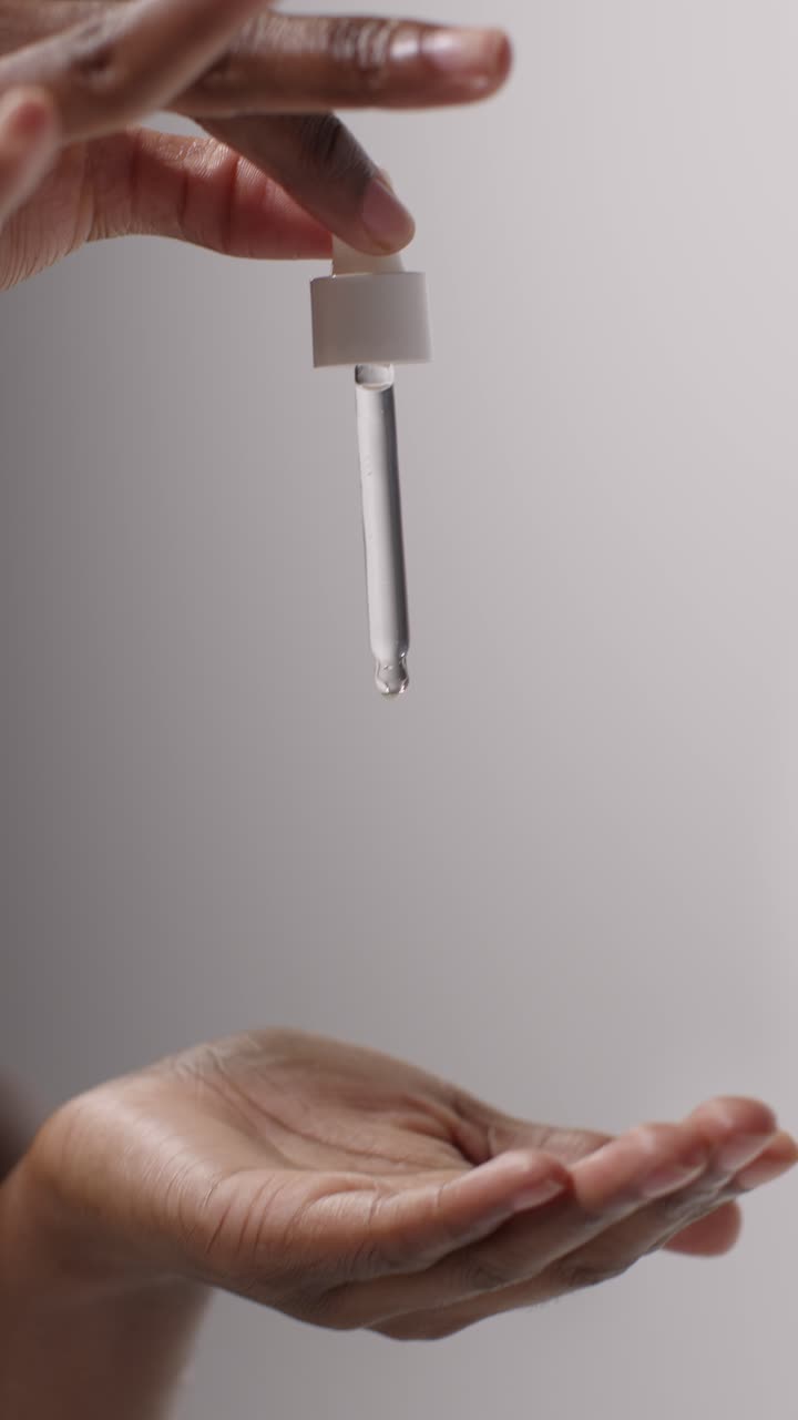 primer plano de una mujer exprimiendo el gotero de una botella de producto de belleza sobre un fondo blanco 4