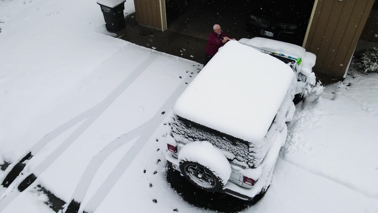 un hombre limpiando la nieve polvo de su vehículo.