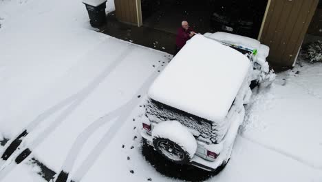 a man cleaning the powdery snow off his vehicle