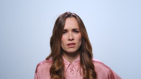 Displeased-businesswoman-gesturing-on-blue-background.-Woman-looking-at-camera