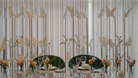 elegant dining setup with green chairs, white floral arrangements, and crystal glassware