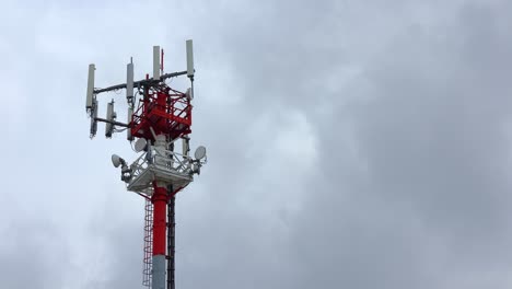 red and white telecommunication antenna tower with signal repeater, cloudy sky, 4k timelapse