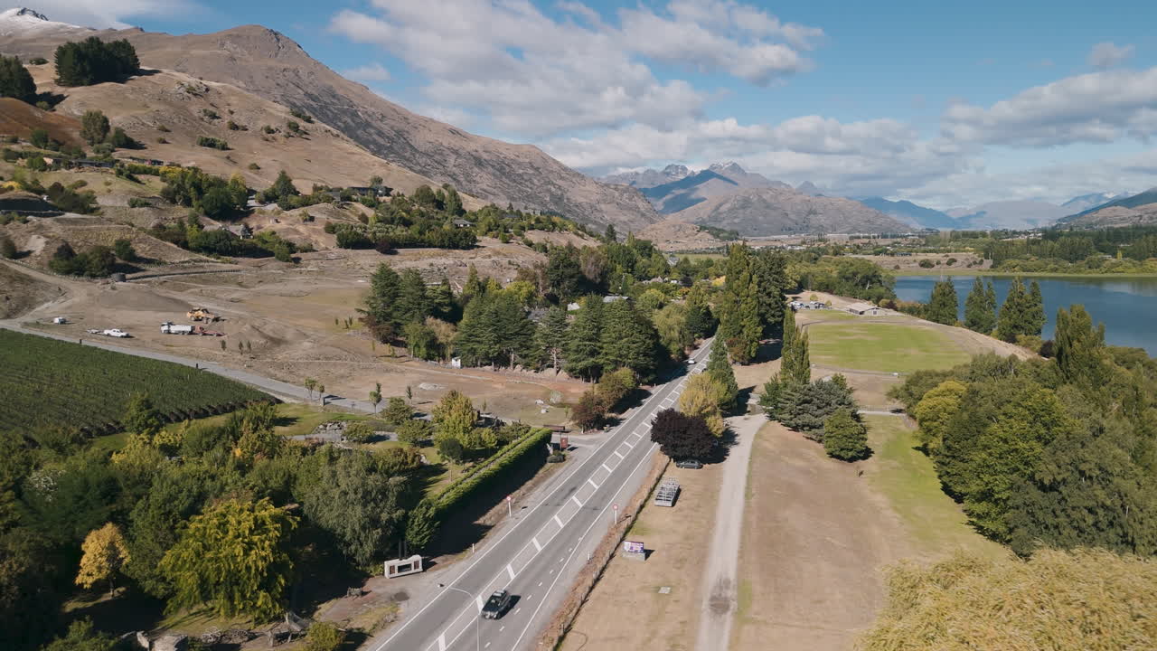 Aerial view of a scenic valley with a lake, mountains, and road in New Zealand