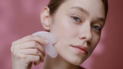 woman using gua sha facial massage stone