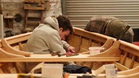 skilled craftsmen working on copper riveting wooden boat