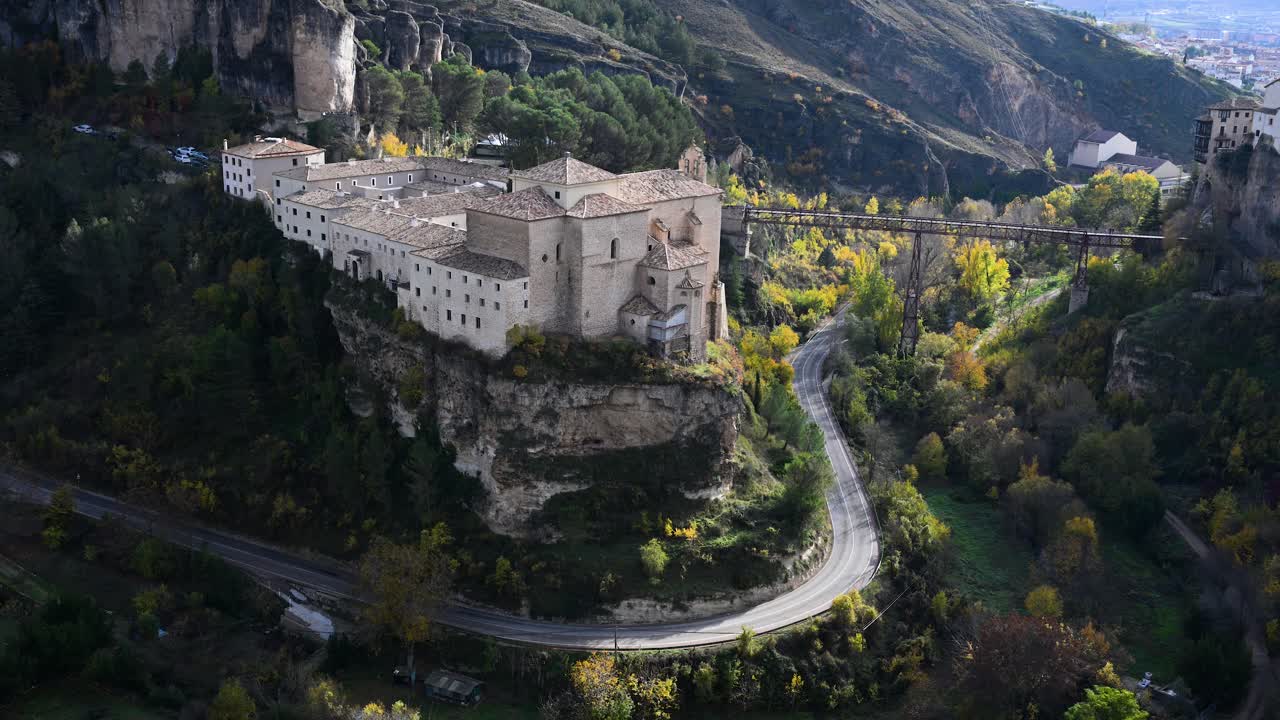 CUENCA, SPAIN - A high-angle view of the Parador de Cuenca and the San Pablo Bridge crossing the Huecar gorge, surrounded by the stunning colors of autumn foliage.