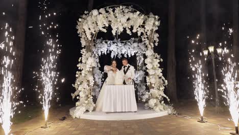 Newlyweds-cut-the-wedding-cake,-lovely-bride-and-groom-couple-cutting-dessert-with-a-knife-outdoors