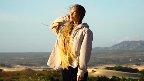 a woman sorting her long out in the wind with beautiful background scenery in phan rang, vietnam on a summer's day