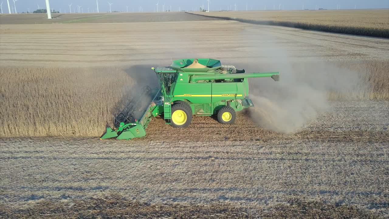 un agricultor del medio oeste cosechando un campo de soja con una cosechadora, un tractor y un vagón de barrena
