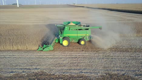 a midwest farmer harvesting a soybean field with a combine, tractor, and auger wagon