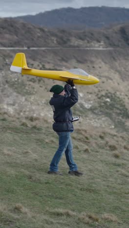 man with a model airplane on a hillside