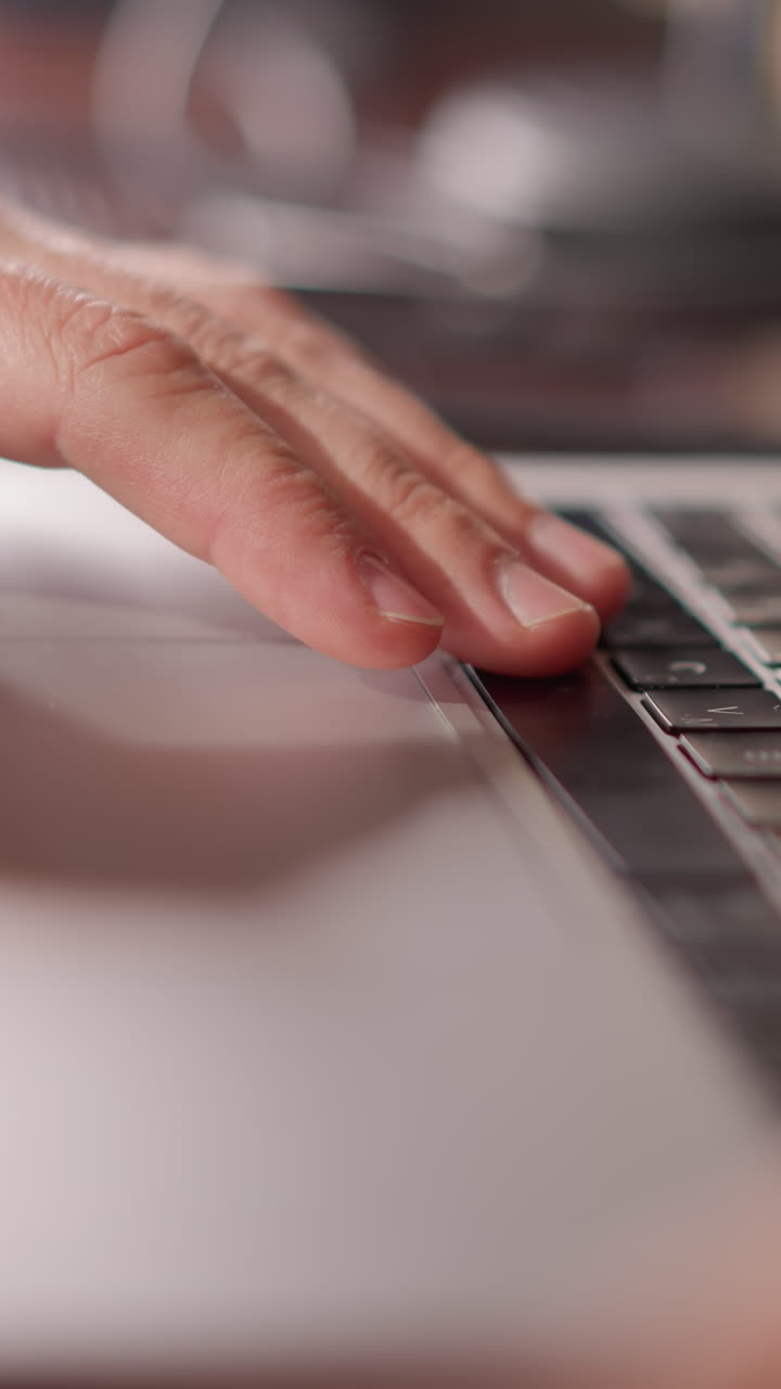 primer plano de una mano descansando en un teclado de computadora, con un fondo borroso que sugiere un espacio de trabajo enfocado y productivo