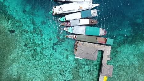 Kreisen-Direkt-über-Den-Touristenbooten-Am-Pier-Auf-Der-Exotischen-Insel-Kanawa,-Labuan-Bajo,-Indonesien