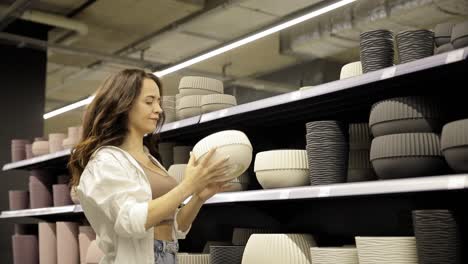 a woman is shopping, she buys ceramic dishes. shop with various utensils for the kitchen. vertical video