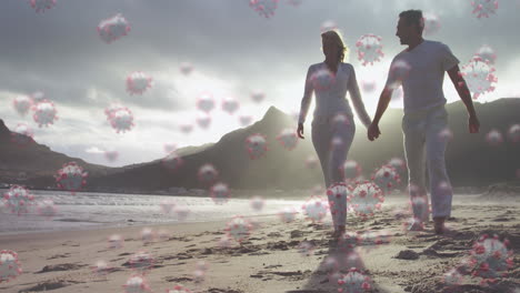 video compuesto digital de células de covid-19 que se mueven contra una pareja caminando por la playa en el fondo