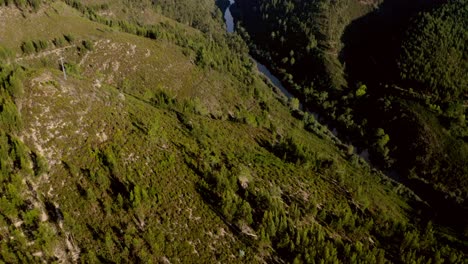 4K-aerial-footage-of-flying-over-a-beautiful-green-forest-with-a-river-in-a-mountain-landscape,-Portugal