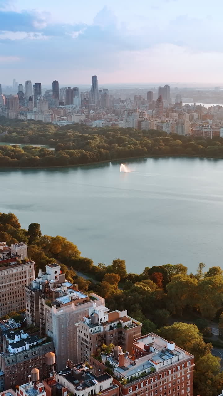 Smooth surface of the water reservoir in Central Park, New York. Beautiful scenery of marvelous city and green area at sunset. Vertical video