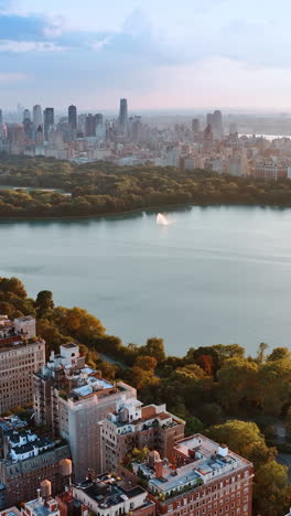 smooth surface of the water reservoir in central park, new york. beautiful scenery of marvelous city and green area at sunset. vertical video