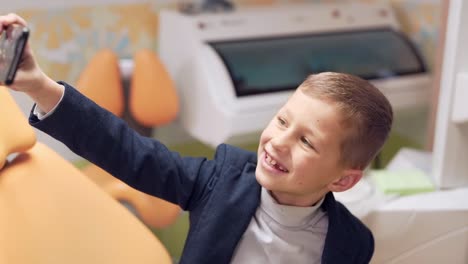 little guy taking a selfie on the phone in the dental office