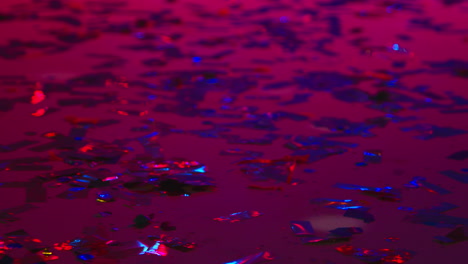 close up de confeti brillante en el piso de un bar de club nocturno o discoteca con iluminación estroboscópica intermitente 1