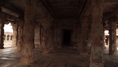 pan view of rock pillars with architecture inside the shri krishna temple at hampi