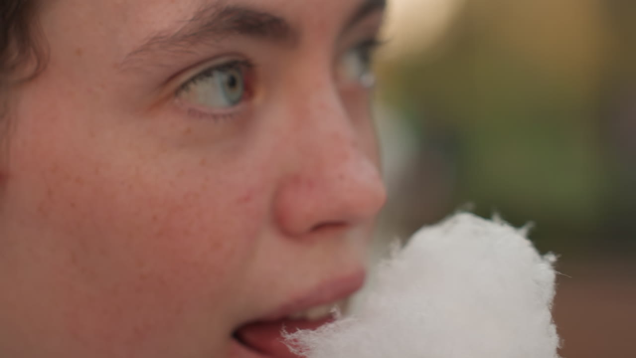 Donna con un dolce. Donna che si gode un vivace festival assaggiando una soffice confetteria zuccherata. Scena spontanea di una donna che prova gioia assaporando zucchero filato a un festival energico.