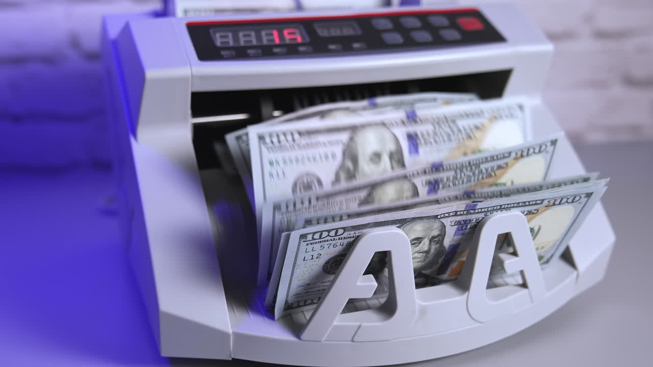 a cash count machine counts US 100 dollar bills